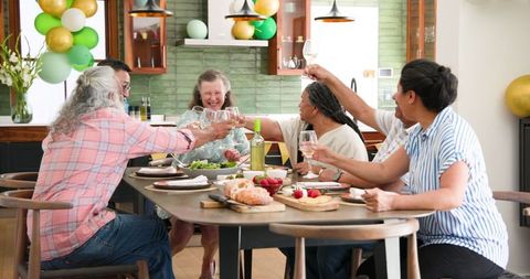 Joyful Senior Friends Toasting at Home Dinner Party Celebration