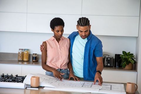 Couple reviewing architectural blueprints in modern kitchen setting