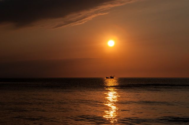 Silhouette of fishing boat under golden sunset on calm sea - Download Free Stock Photos Pikwizard.com