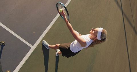 Aerial Tennis Serve by Woman on Outdoor Court Tossing Ball and Raising Racket