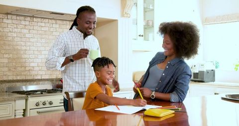 Family bonding while assisting son with homework at kitchen table