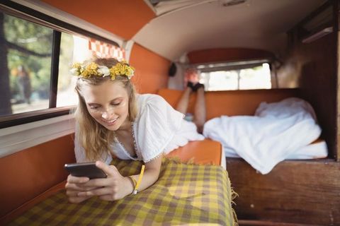 Bohemian woman relaxing in vintage camper with smartphone