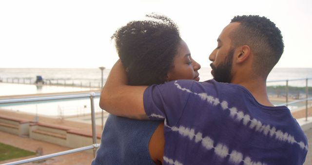 Romantic diverse couple sitting and embracing on sunny promenade, copy space. Summer, vacation, romance, love, relationship, free time and lifestyle, unaltered.