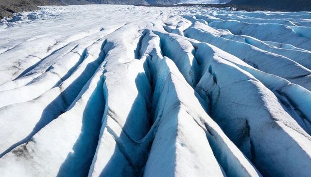 Jagged crevasse ridges on blue glacier ice, deep fissures carving alpine glacier surface