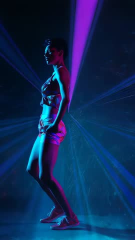 Futuristic dancer rotating under magenta spotlight and laser beams | Vertical video