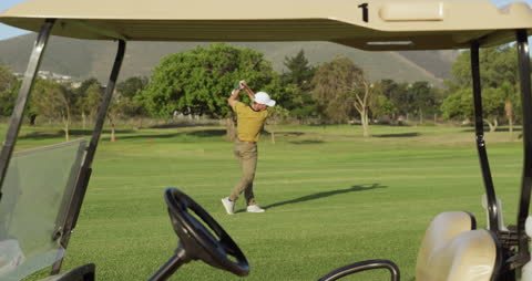 Golfer Swinging on Verdant Golf Course Through Buggy View