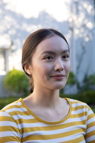 Confident Woman in Striped Shirt Posing in Serene Garden