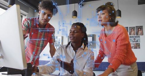 Collaborating team analyzing holographic data on desktop monitor in creative tech office