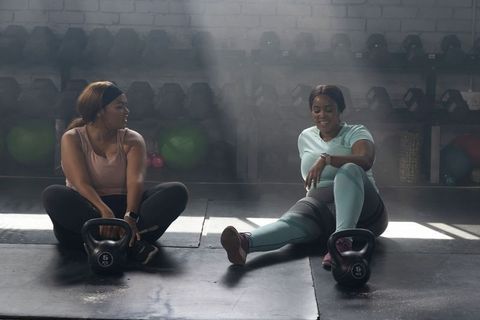 African american women stretching with kettlebells in fitness studio smiling partners
