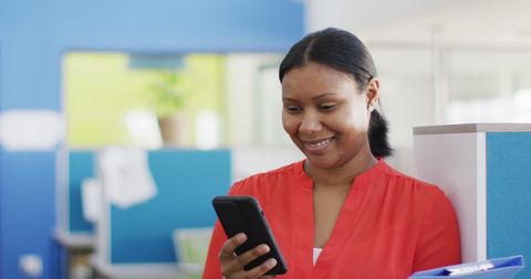 Businesswoman Smiling at Smartphone in Office Environment