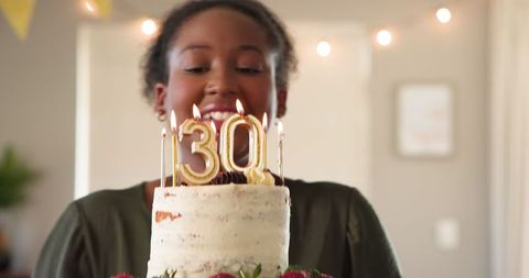 Smiling Woman Holds Cake with 30th Birthday Candles