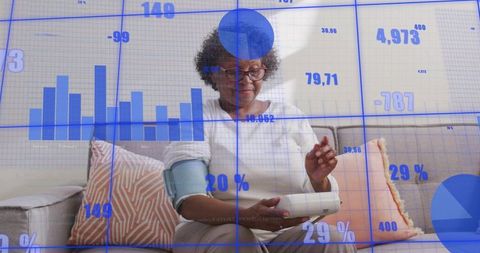 Senior woman monitoring blood pressure at home using tablet and telehealth dashboard