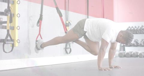Man performing suspended trx plank with knee drive for core stability training