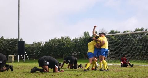 Soccer team celebrating victory goal in front of goalpost
