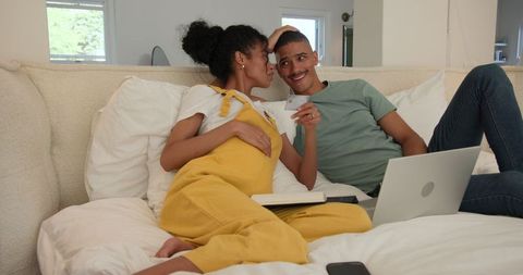 Multicultural couple relaxing with laptop on cozy sofa