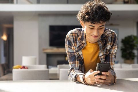 Young man using smartphone in modern home kitchen