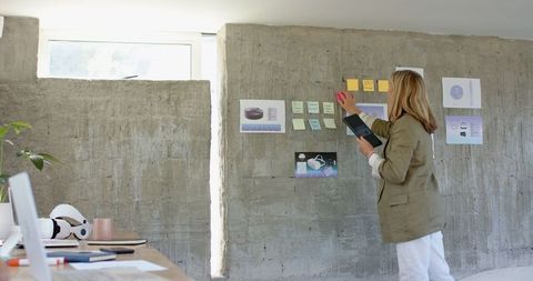 Professional woman organizing creative ideas on office wall