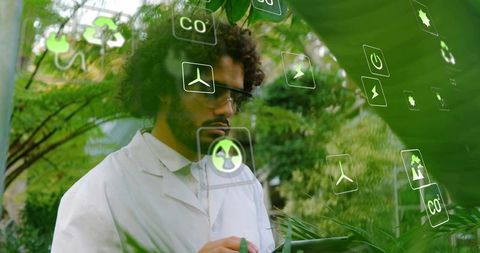 African american scientist using tablet with ar icons in sustainable greenhouse