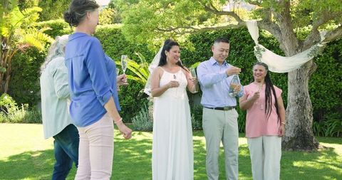 Happy Senior Couple Toasting With Friends in Garden Celebration