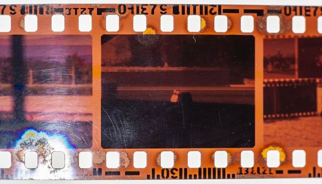 Vintage 35mm negative film strip showing scratches, sprocket holes and rainbow flare