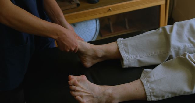 Image shows a therapist performing a foot massage on a person. Ideal for use in wellness, health, and spa-related content. Suitable for articles and promotions about stress relief, holistic healing, and alternative medicine. Can also be used in physical therapy and self-care guides.