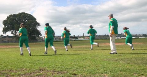 Women's softball team warming up with coach on field