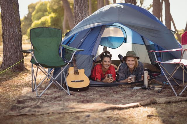 Portrait of happy couple relaxing in tent at forest
