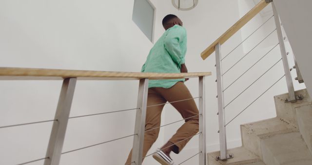 African American man climbing stairs in an indoor setting. He's taking steps towards his destination with purpose and determination.