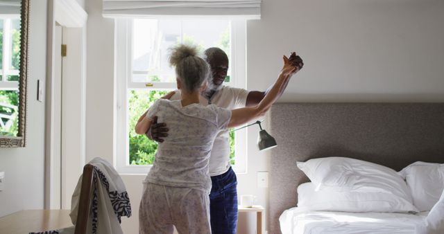 Biracial senior couple dancing together in the bedroom at home. retirement senior couple lifestyle living self isolation in quarantine lockdown