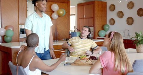 Friends engaging in conversation around kitchen table with snacks