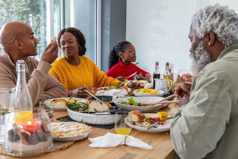 African American Multigenerational Family Sharing Roast Dinner Laughing Together at Home
