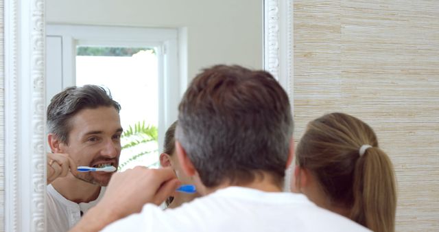 Couple Brushing Teeth Together in Bathroom Mirror - Download Free Stock Images Pikwizard.com