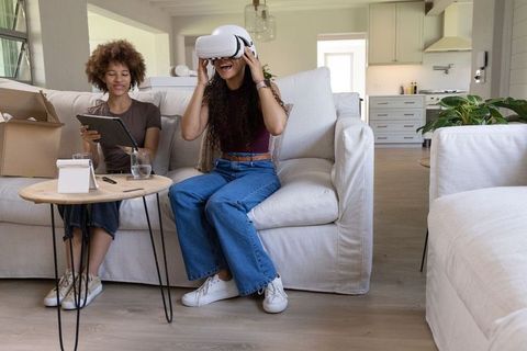 African friends trying virtual reality headset at home while unboxing tech and laughing