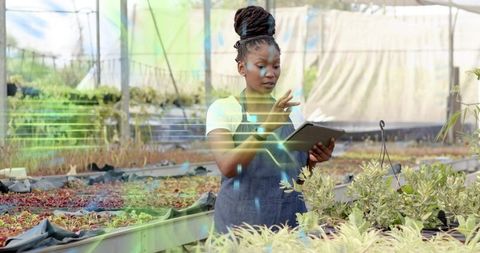 Innovative Horticulturist Swiping Tablet in Sustainable Greenhouse