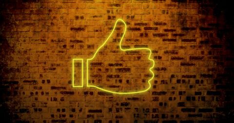 Glowing Neon Thumbs Up Icon on Textured Brick Wall