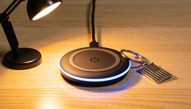 Glowing black wireless charger with blue led ring and american flag keychain on wood desk