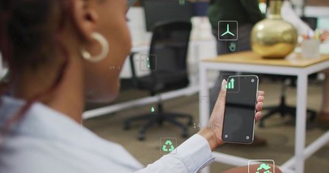 Holding phone and viewing augmented reality icons in modern office workspace for productivity