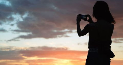 Silhouette of Woman Capturing Sunset with Smartphone on Beach - Download Free Stock Images Pikwizard.com
