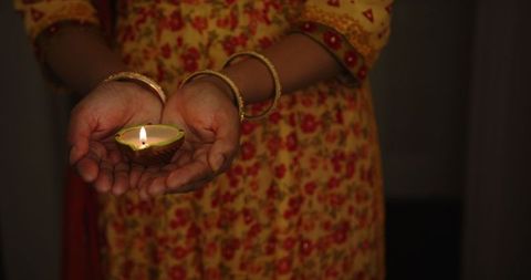 Indian woman celebrating diwali with traditional lit diya