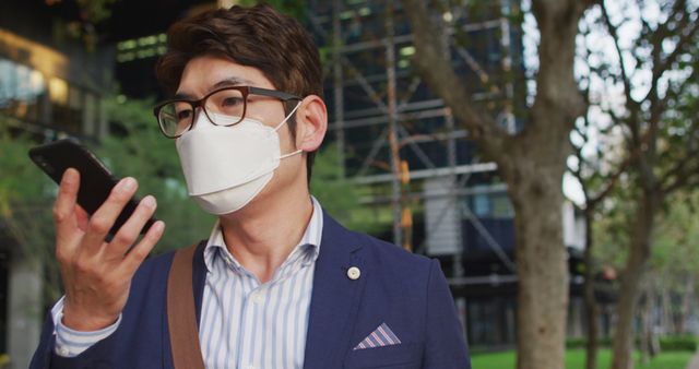 Asian man wearing face mask talking on smartphone while walking on the street. health protection and safety during covid-19 pandemic concept