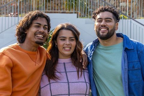 Young diverse friends smiling and embracing on outdoor steps in casual colorful outfits
