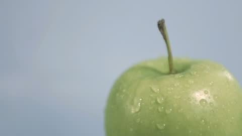 Refreshing Water Droplets on Green Apple Against Blue Background
