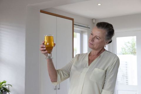 Senior Woman Examining Beverage Glass in Contemporary Kitchen