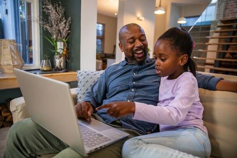 Warm african american father and daughter bonding over laptop, learning and laughing together