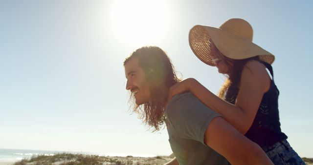 Couple Enjoying Piggyback Ride on Sunny Beach Day - Download Free Stock Images Pikwizard.com