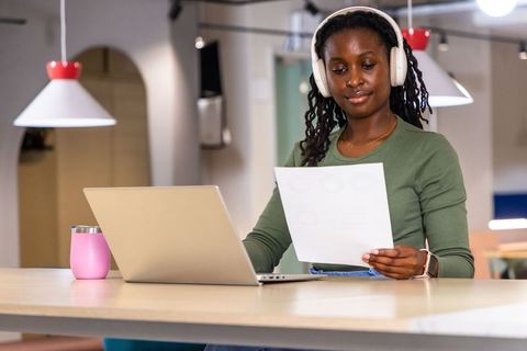 African american woman working remotely with headset and laptop in modern coworking space