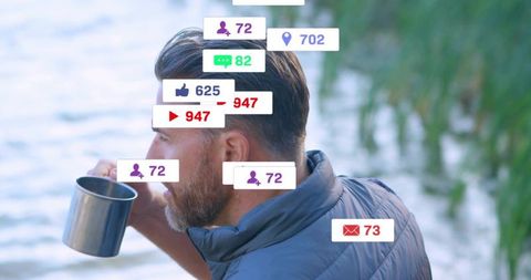 Bearded man sipping from stainless steel mug by lake, social media notification overlays