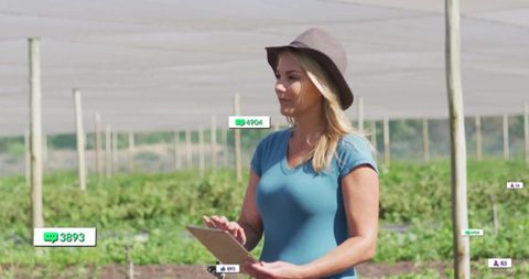 Farm manager recording crop data under shade netting