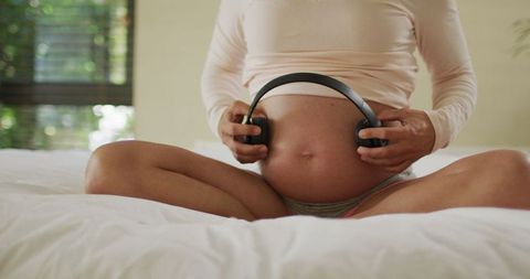 Pregnant Woman Using Headphones on Belly for Unborn Baby's Music Therapy