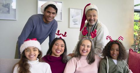 Multigenerational family celebrating Christmas wearing Santa hats, reindeer antlers